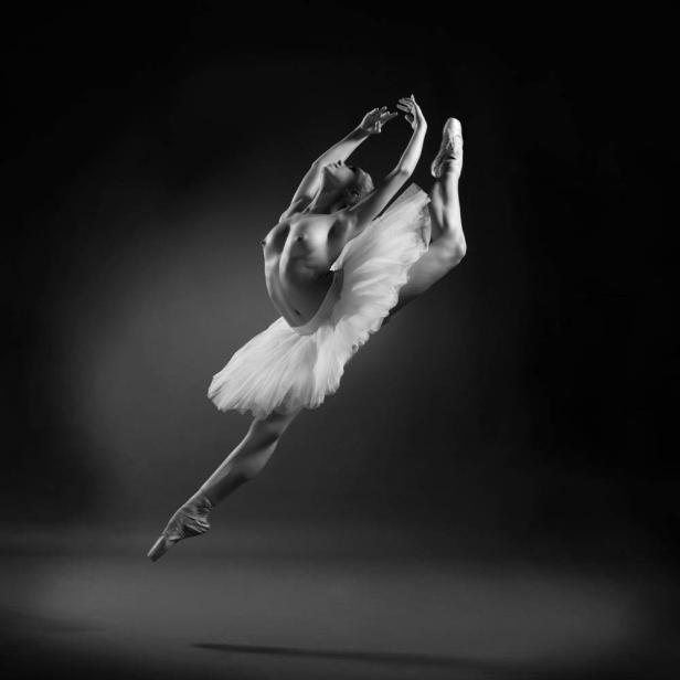 Eine Ballerina in einem weißen Tutu springt anmutig in der Luft.