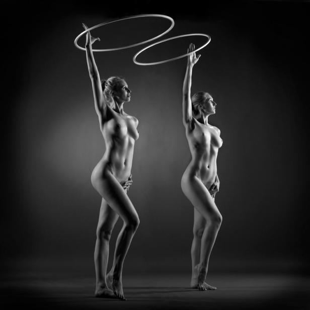 Zwei Frauen posieren nackt mit Hula-Hoop-Reifen in einem Schwarz-Weiß-Foto.
