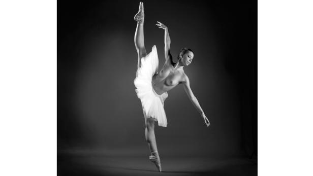 Eine Ballerina in Tutu und Spitzenschuhen führt eine anspruchsvolle Ballettpose aus.