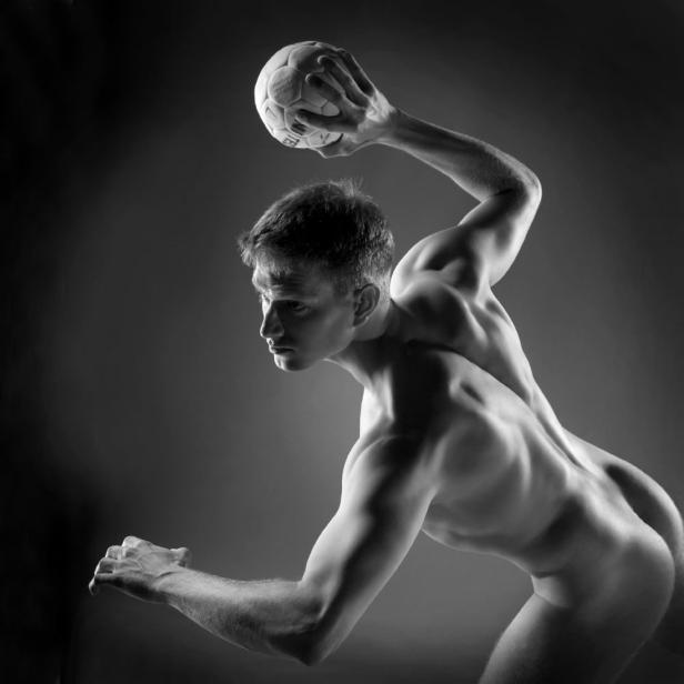 Ein muskulöser, nackter Mann im Profil bereitet sich darauf vor, einen Ball zu werfen.