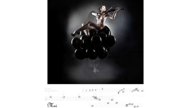 Eine Frau sitzt auf einem Haufen schwarzer Ballons und spielt Geige.