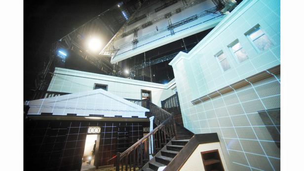 Blick auf ein Filmset mit einem Haus und Beleuchtungstechnik.