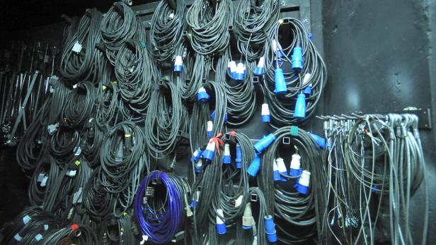 Viele zusammengerollte Kabel hängen an einer Wand.