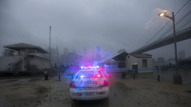 Ein Polizeiauto mit eingeschalteten Lichtern steht vor der Skyline von New York City.