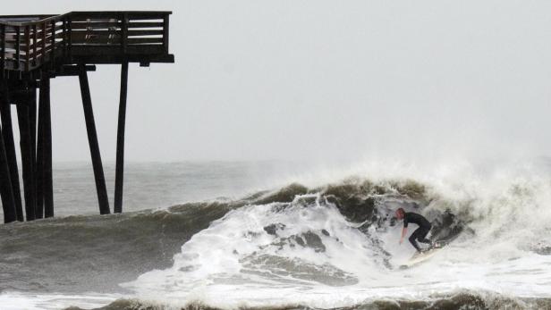 Ein Surfer reitet auf einer Welle in der Nähe eines Piers.