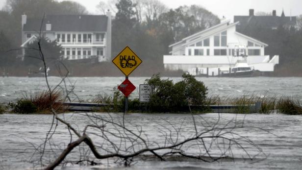 Hochwasser hat eine Straße überschwemmt, im Hintergrund Wohnhäuser.