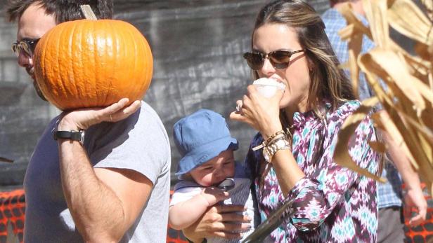 Alessandra Ambrosio isst Eis, während ein Mann einen Kürbis trägt und ein Baby gehalten wird.