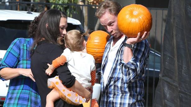 Eine Familie mit einem kleinen Kind sucht Kürbisse für Halloween aus.