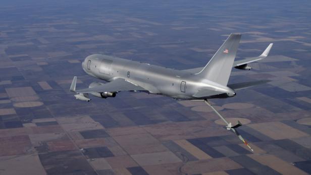 Ein Tankflugzeug betankt ein anderes Flugzeug über Feldern.
