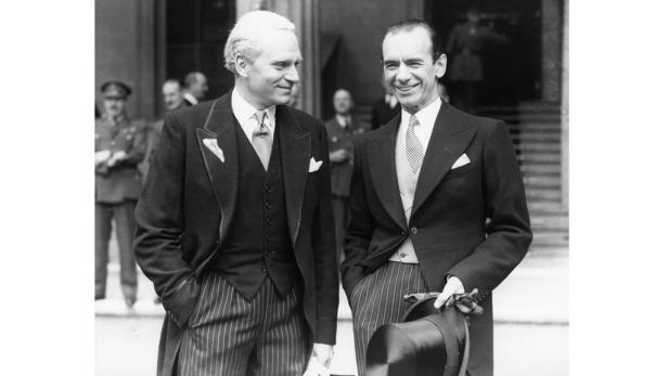 Zwei elegant gekleidete Männer in Anzügen stehen zusammen.