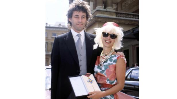 Ein Mann im Anzug und eine Frau mit Sonnenbrille halten eine Auszeichnung.