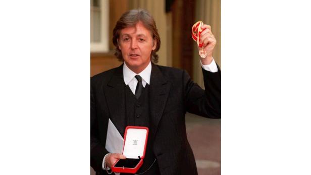 Paul McCartney hält eine Medaille und deren Etui in den Händen.