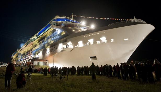 Eine große Menschenmenge betrachtet nachts das Kreuzfahrtschiff „Equinox“.