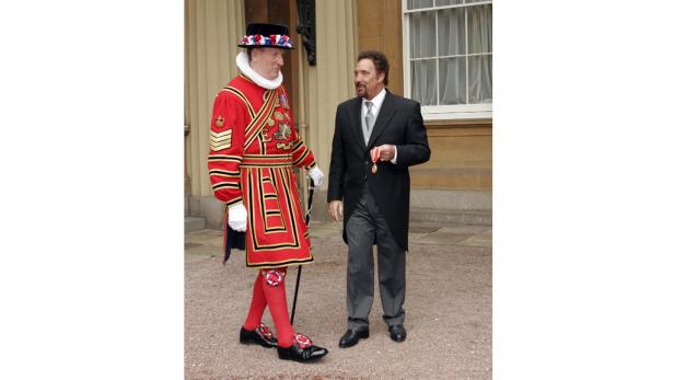 Tom Jones steht mit einem Mitglied der königlichen Leibgarde vor einem Gebäude.