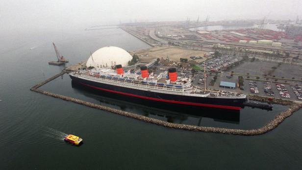Die Queen Mary liegt in Long Beach vor Anker, neben einem Parkplatz und einem geodätischen Dom.