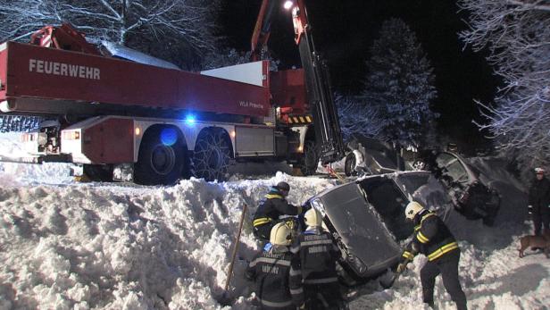 Ein Feuerwehrkran birgt ein Auto nach einem Unfall im Schnee.