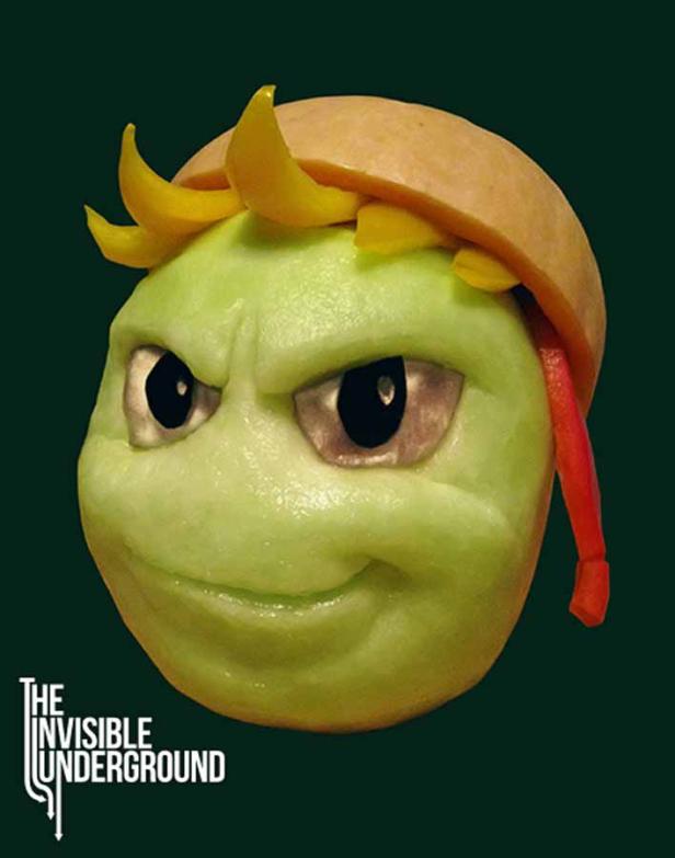 Ein grüner Apfel wurde als Gesicht mit gelben Paprikaschoten als Haare und einer Melonenkappe geschnitzt.