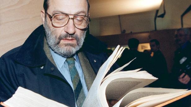 Ein Mann mit Brille und Bart liest in einem dicken Buch.