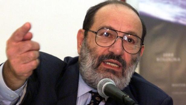 Ein Mann mit Bart und Brille gestikuliert vor einem Mikrofon.