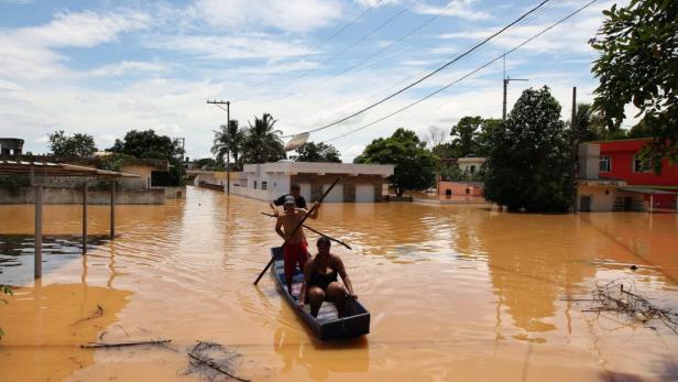 Menschen fahren mit einem Boot durch eine überflutete Straße.