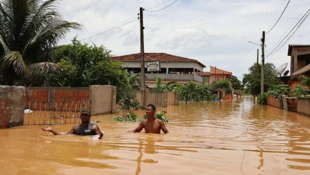 Zwei Männer stehen in einer überfluteten Straße in Brasilien.