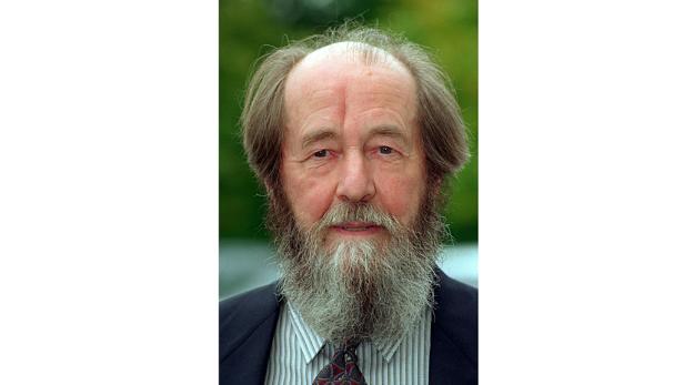 Porträt eines Mannes mit Bart und Anzug.