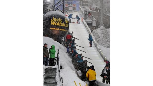 Skifahrer stehen bei Schneefall an einem Jack Wolfskin Werbeball vorbei an einem Skilift in Bischofshofen an.