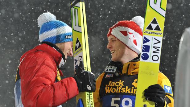 Zwei Skispringer mit Skiern geben sich bei Schneefall ein High-Five.