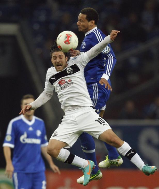 Zwei Fußballspieler kämpfen in der Luft um den Ball.