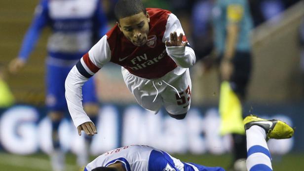 Ein Fußballspieler von Arsenal springt über einen am Boden liegenden Gegenspieler.