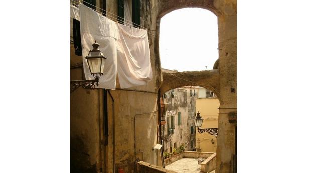 Eine Gasse in einer italienischen Stadt mit Wäscheleinen und alten Laternen.