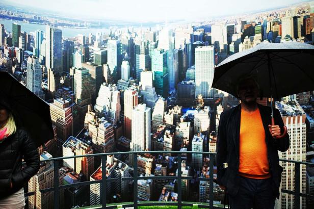 Zwei Personen mit Regenschirmen vor der Skyline von New York City.