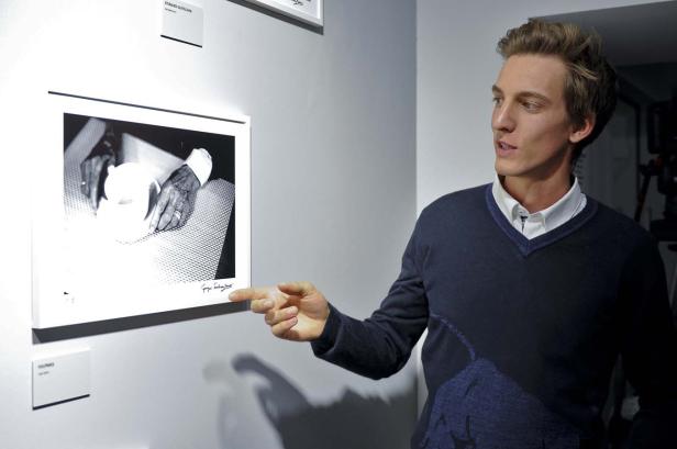 Ein Mann deutet auf ein Schwarz-Weiß-Foto an einer Wand.