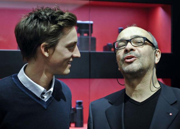 Zwei Männer unterhalten sich vor einem roten Hintergrund.