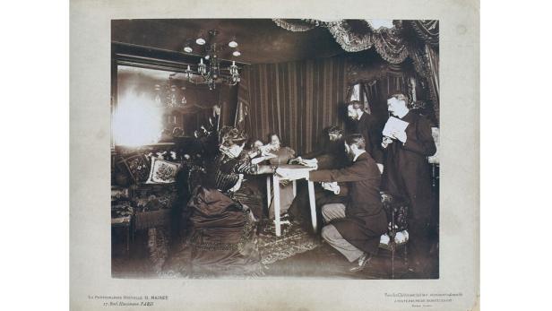 Eine Gruppe von Menschen sitzt um einen Tisch und nimmt an einer Séance teil.