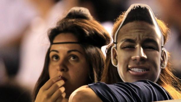 Eine Frau isst, während eine andere eine Neymar-Maske trägt.