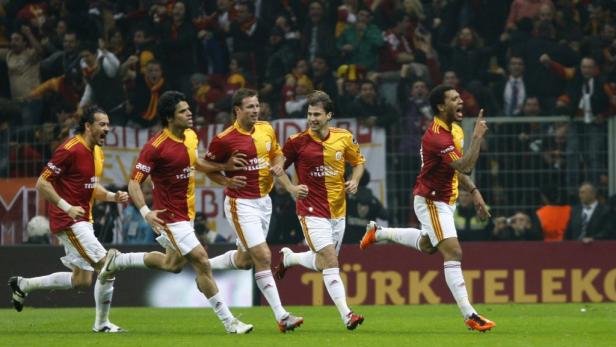 Mehrere Fußballspieler von Galatasaray jubeln auf dem Spielfeld vor den Fans.