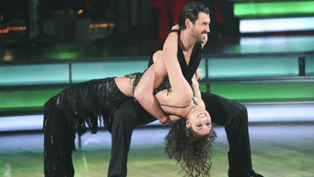 Ein Mann hält eine Frau bei einer Tanzdarbietung über seinen Rücken geneigt.