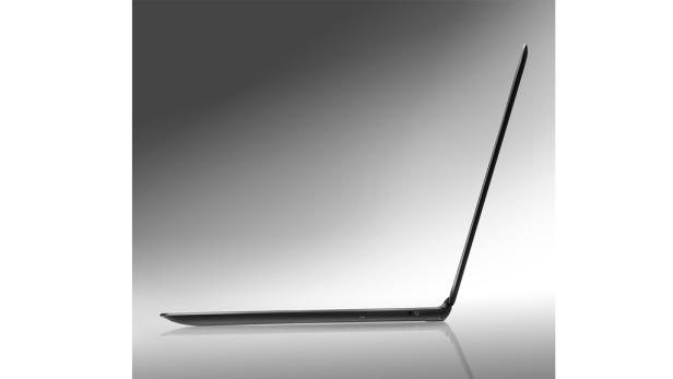 Ein schlanker, schwarzer Laptop steht seitlich auf einer glänzenden Oberfläche.