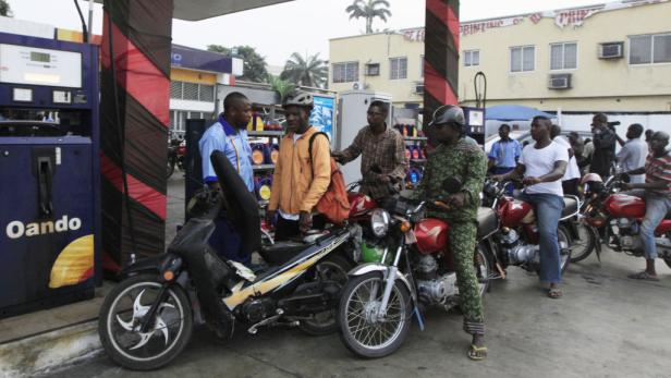 Mehrere Motorradfahrer tanken an einer Tankstelle der Marke Oando.