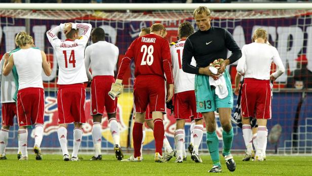 Eine Gruppe Fußballspieler steht nach dem Spiel enttäuscht auf dem Rasen.