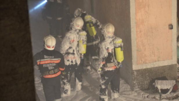 Feuerwehrleute in voller Montur stehen im Schnee vor einem Gebäude.