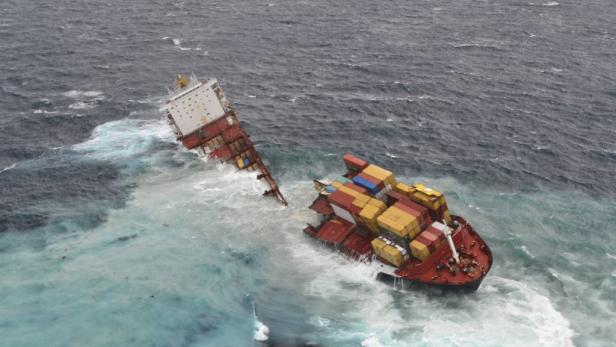 Ein in zwei Teile zerbrochenes Containerschiff treibt im stürmischen Meer.