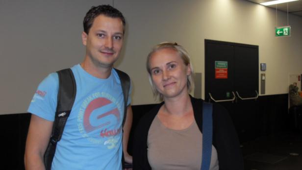 Ein Mann mit Rucksack und eine Frau stehen in einem Gebäude.