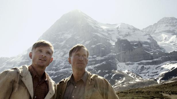 Zwei Männer stehen vor einer beeindruckenden Bergkulisse.