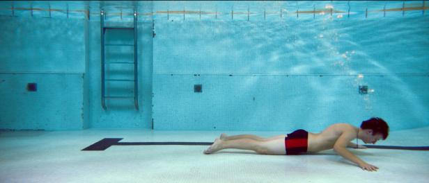 Ein Mann liegt auf dem Grund eines Schwimmbeckens.