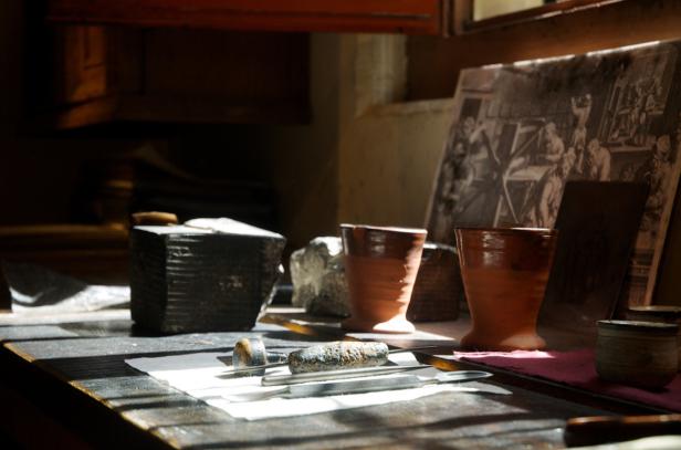 Ein Tisch mit Werkzeugen, Tassen und einem Bild in einem hell erleuchteten Raum.