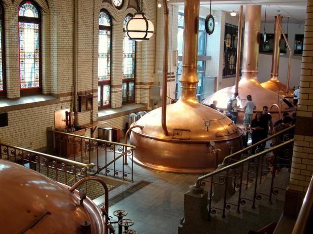 Innenansicht einer Brauerei mit großen Kupferkesseln und Besuchern.