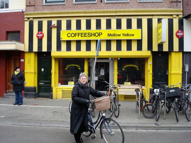 Eine Frau schiebt ihr Fahrrad vor einem Coffeeshop namens „Mellow Yellow“.
