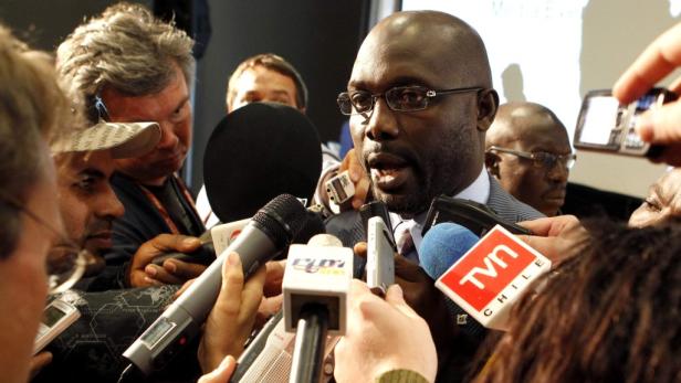 George Weah wird von Reportern umringt.